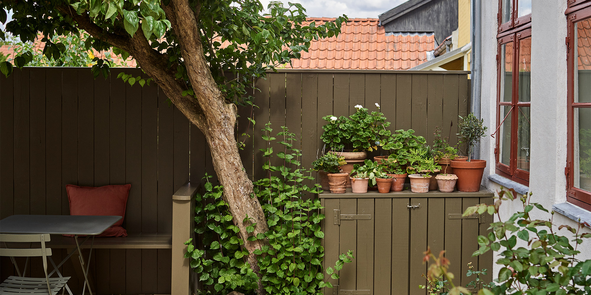 Aussenbereich mit gestrichenen Holzflaechen und Pflanztischen als Beispiel fuer Holz Untergrund