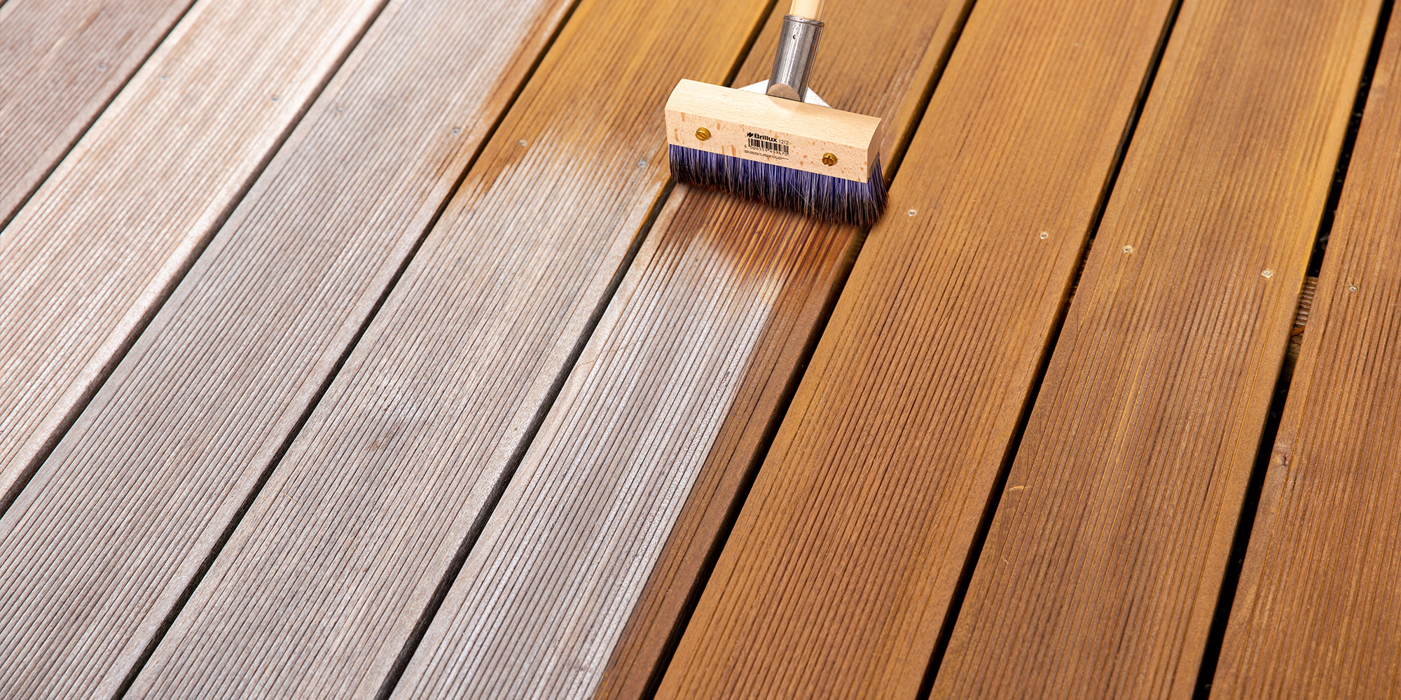 Holzterrasse wird gebürstet, rechts frisch behandeltes Holz neben unbehandelten Dielen