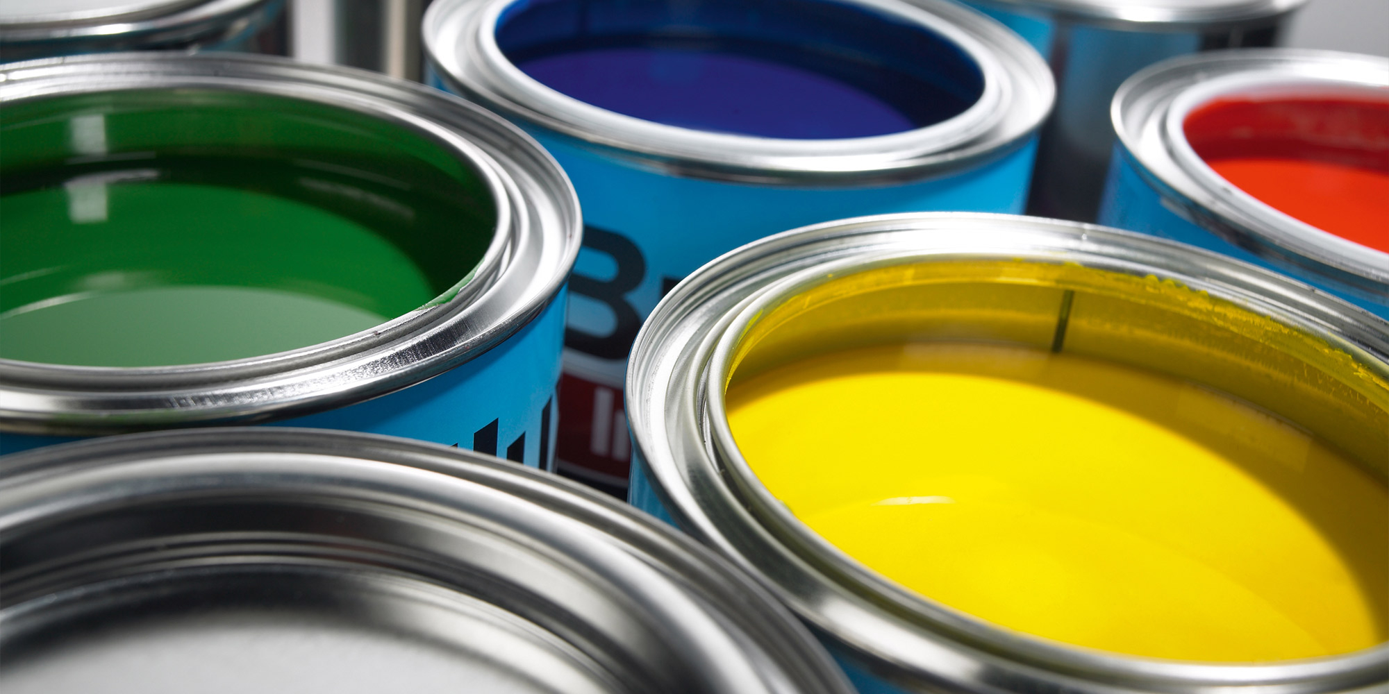 Offene Farbdosen mit Lack in Gelb, Grün, Blau und Rot