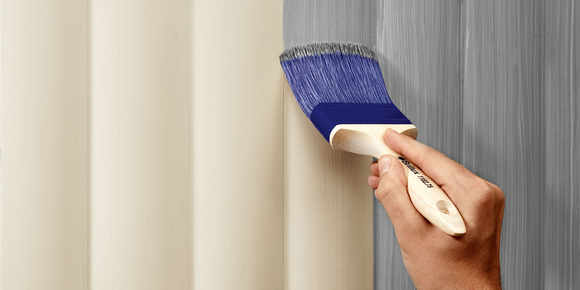 Hand trägt mit Pinsel eine graue Aufhelltechnik auf helle Holzoberfläche auf