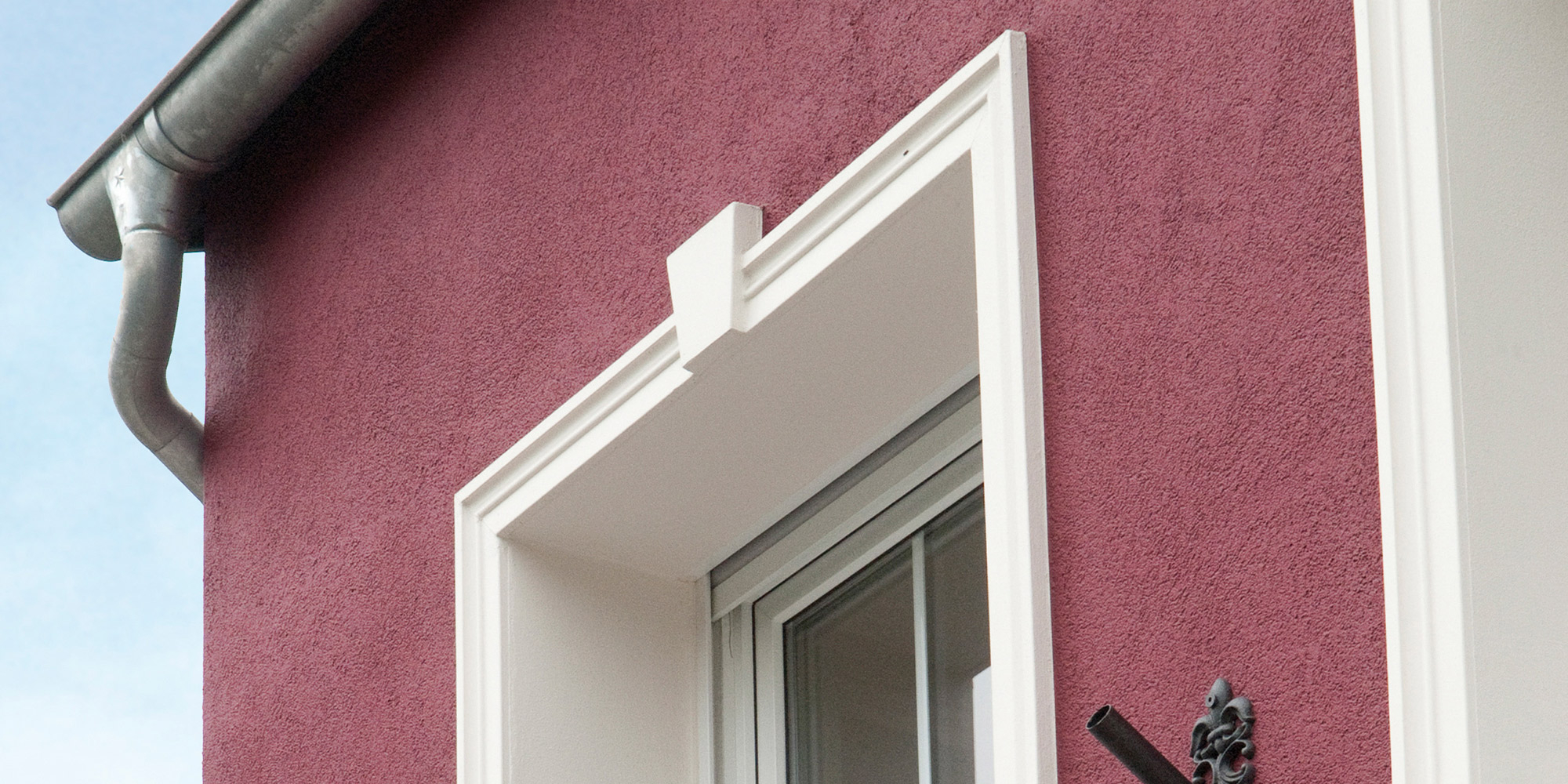 Eine schöne Hausfassade mit einer dekorativen Fensterumrandung aus Stuck.