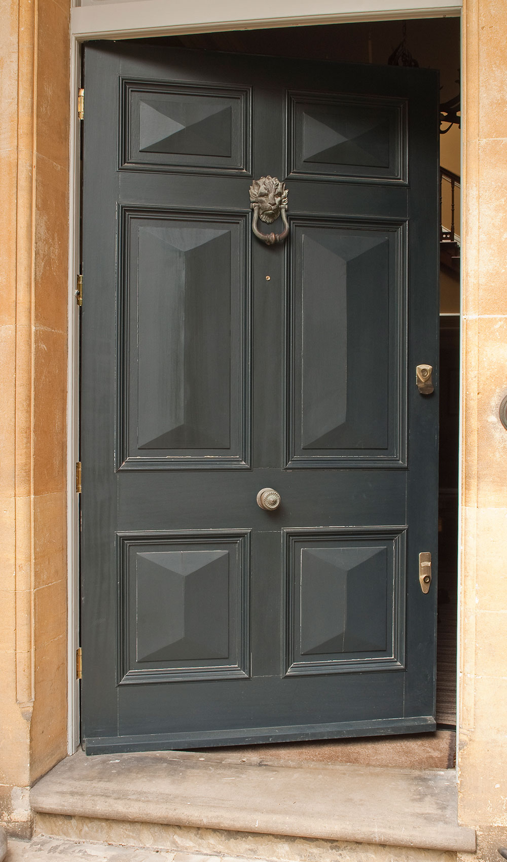 Geöffnete dunkelgraue Holzhaustür mit Kassetten und Löwenklopfer im Steineingang - Ergebnis nach Lackierung