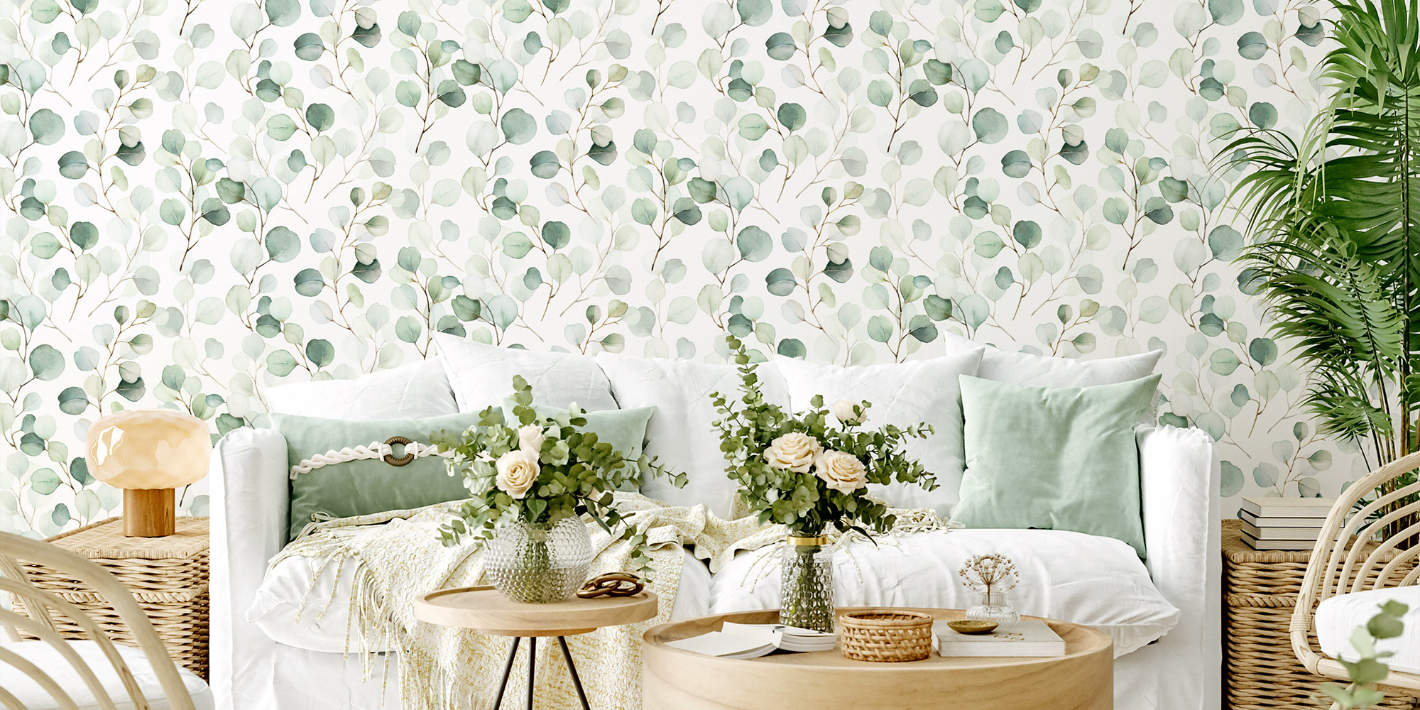  Wohnzimmer mit hellem Sofa vor Wand mit grünem Blättermuster, dekorative Kissen und Pflanzen