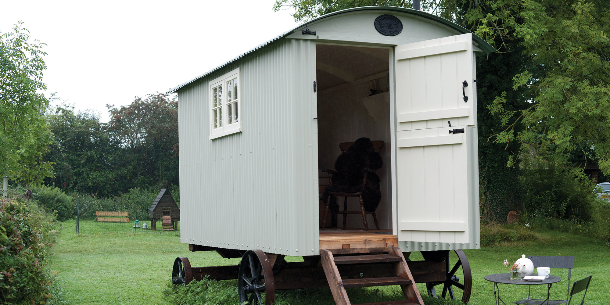 Kleines Gartenhaus auf Rädern mit geöffneter Tür auf einer Wiese