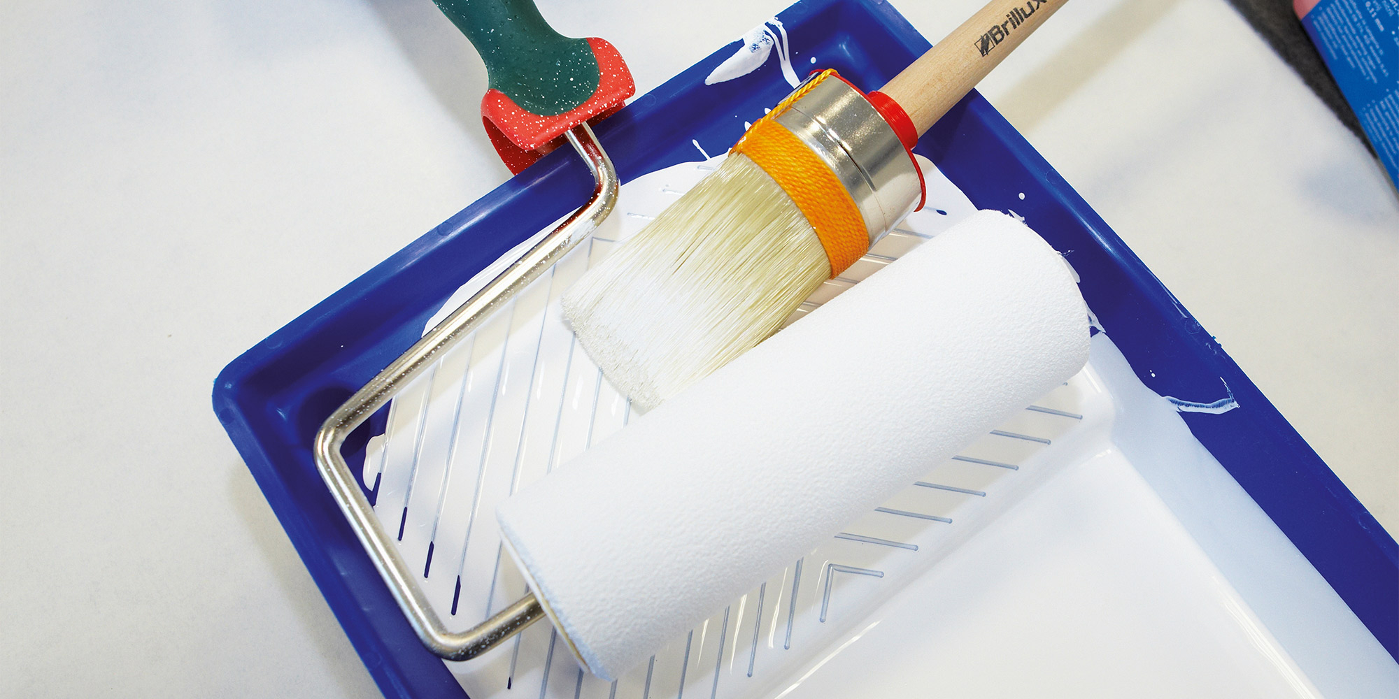 Farbwanne mit Farbrolle und Pinsel fuer Malerarbeiten
