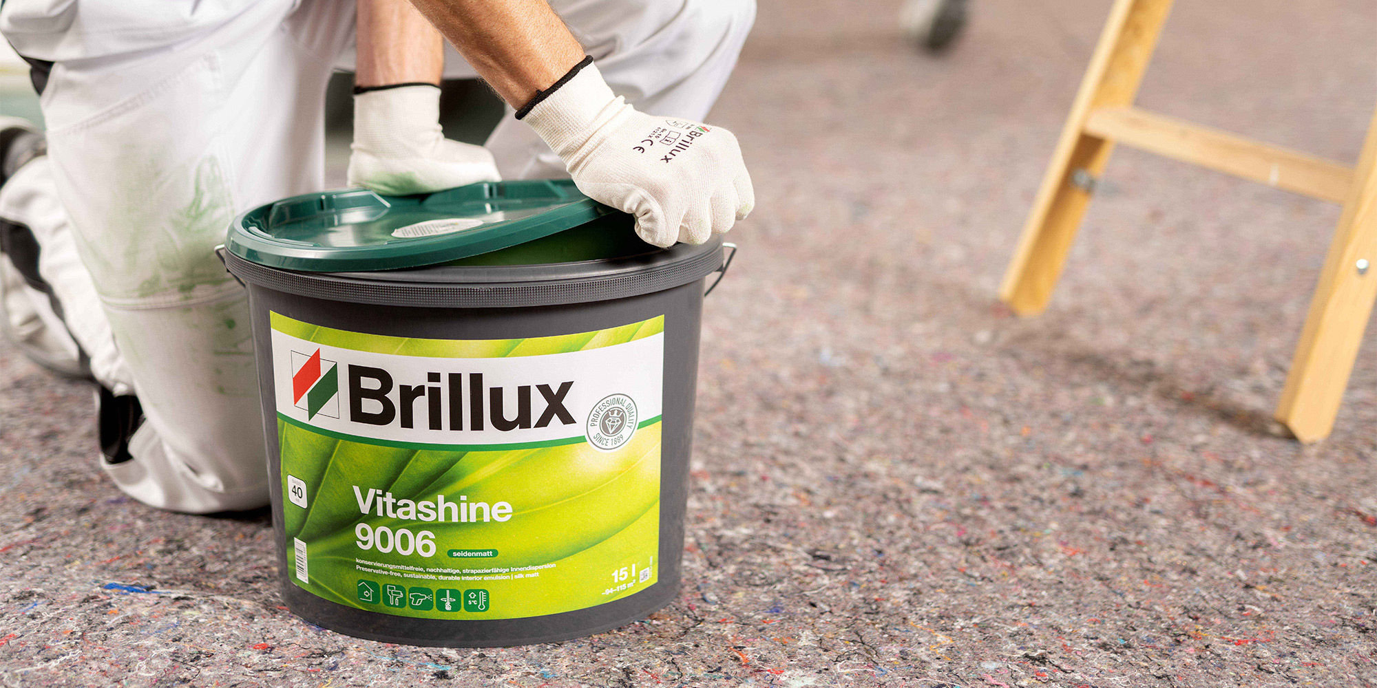Hand oeffnet einen Farbeimer mit Innenfarbe