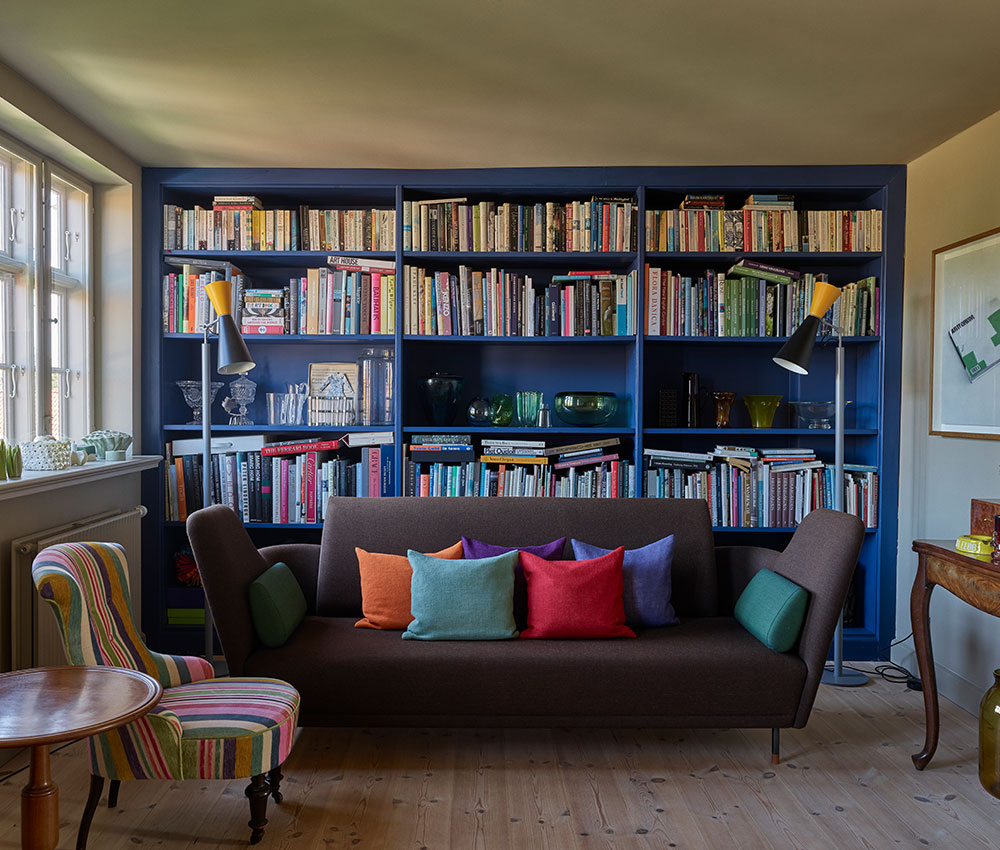 Wohnzimmer mit blau gestrichenem Buecherregal voller Buecher und Sofa - Inspiration fuer Moebel streichen