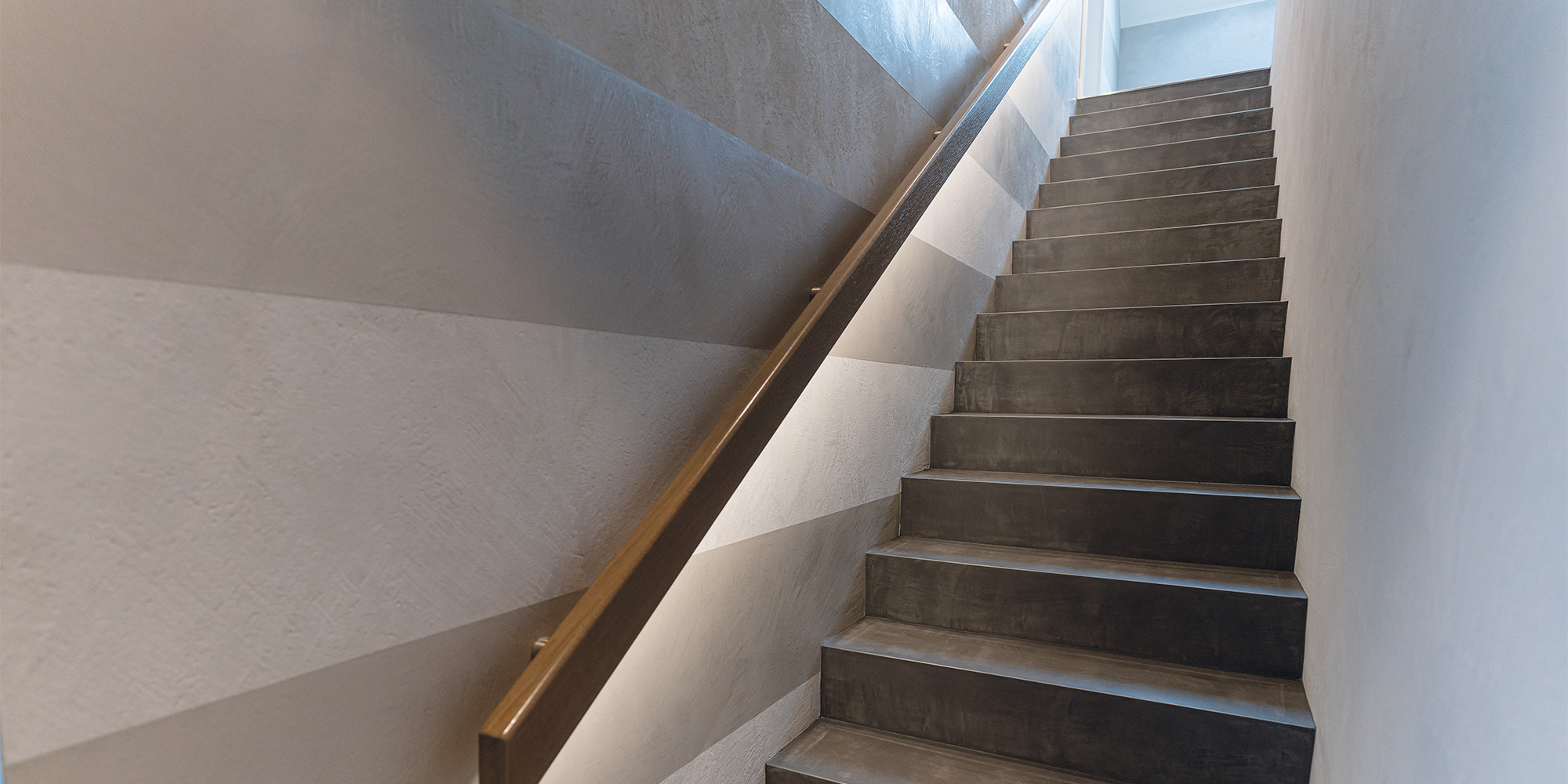 Moderne Treppe mit breiten Stufen und kreativer Wandgestaltung in Streifenoptik mit Frescolori Spachteltechnik