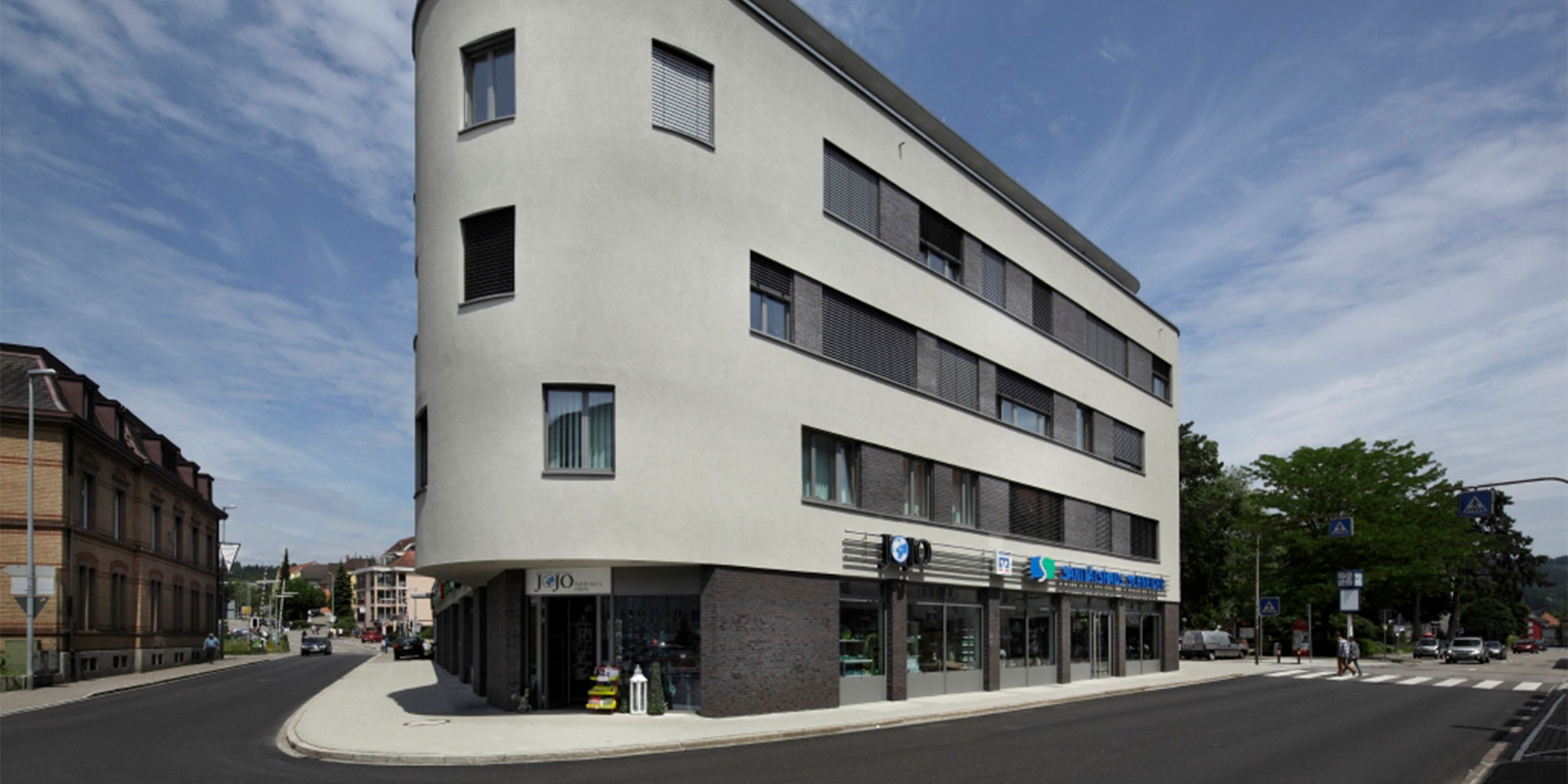 Mehrgeschossiges Gebäude mit heller Putzfassade und dunklen Fensterbändern