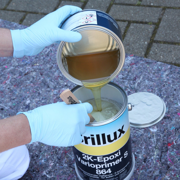 Eine Dose Brillux 2K Epoxi Vario Primer steht auf dem Boden und wird von einem Mann gerade zusammengemischt.